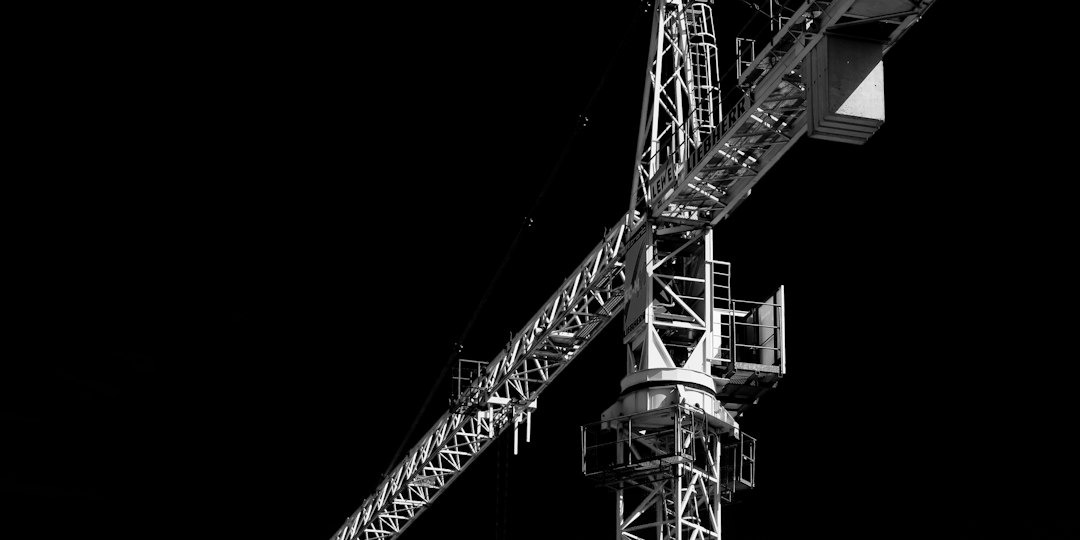 Black and white construction crane structure against a black background.